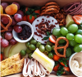 Grapes, cheese, pretzels and dip set up on a charcuterie board.